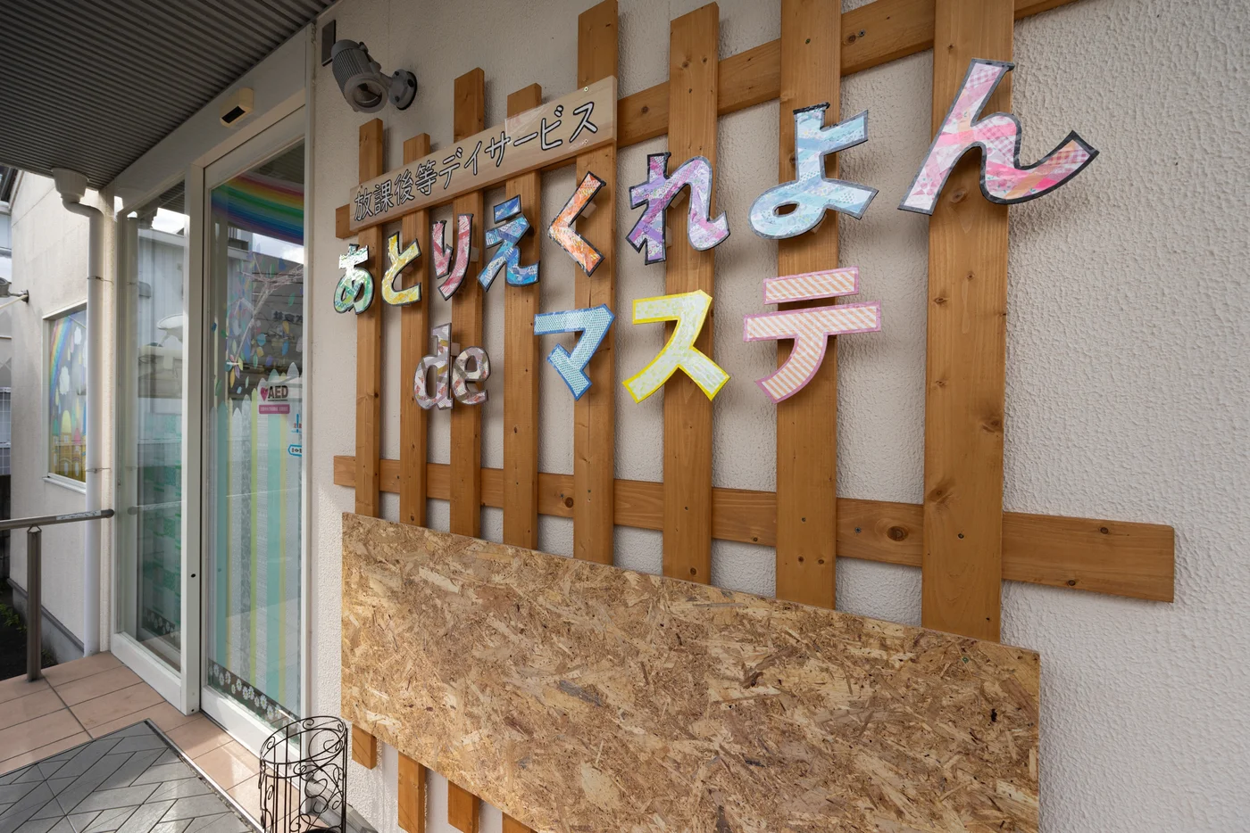 あとりえくれよんdeマステの入口。マスキングテープで彩られた「あとりえくれよんdeマステ」の看板が、木の格子壁に飾られている