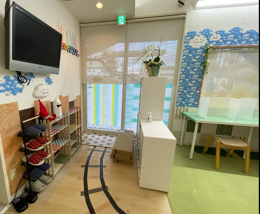玄関。スリッパの棚があり、床には木目にマスキングテープで線路が描かれている。奥は学習スペースへつながる